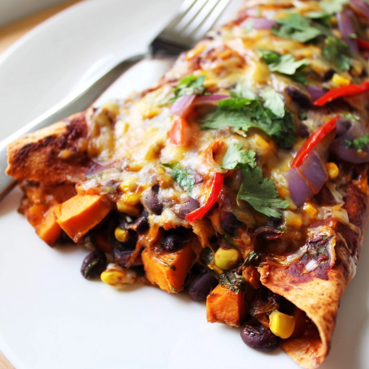 Close-up of Spicy Black Bean & Sweet Potato Enchiladas, bubbling with melted cheese.