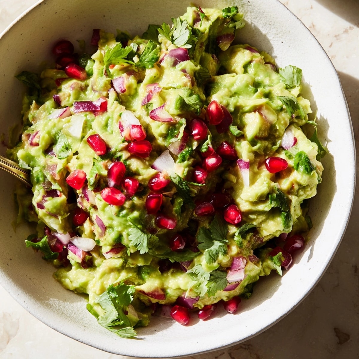 Homemade Pomegranate Guacamole: Mashed avocado with cilantro, jalapeño, and juicy pomegranate seeds.