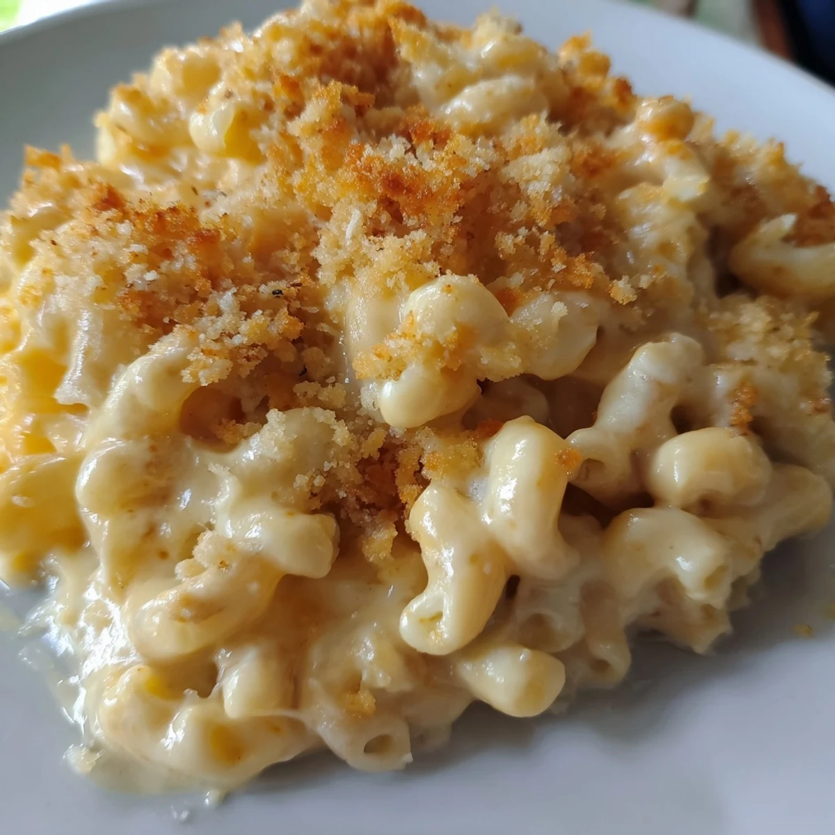 Steaming bowl of creamy macaroni and cheese, topped with golden crispy baked breadcrumbs.