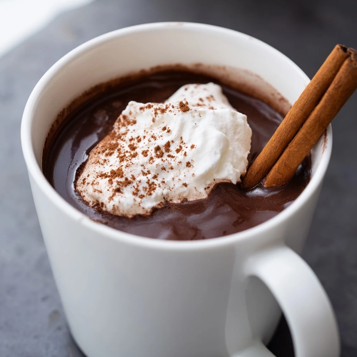 Dark, rich Spiced Hot Chocolate swirled with a cinnamon stick, offering a flavorful sip.