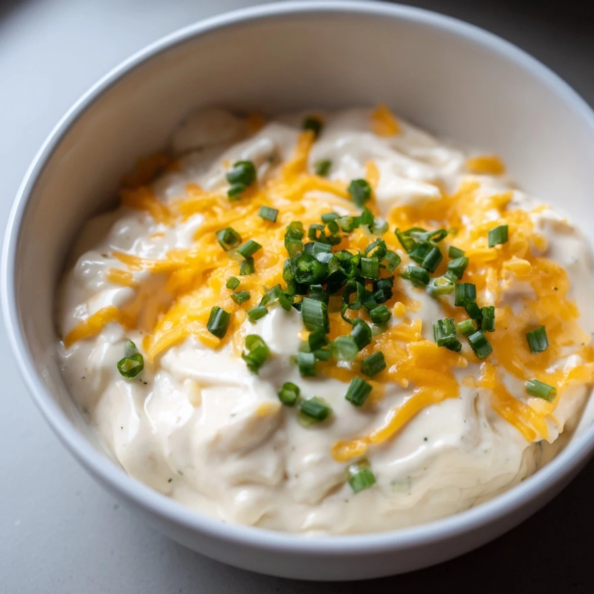 A luscious bowl of this creamy cheese dip, garnished with chives, ready to be devoured.