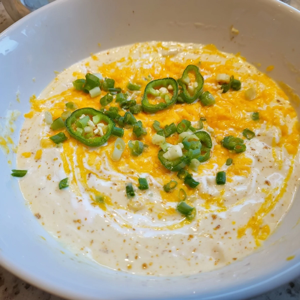 Freshly made creamy cheese dip, a delicious appetizer served in a bowl with crudités visible.