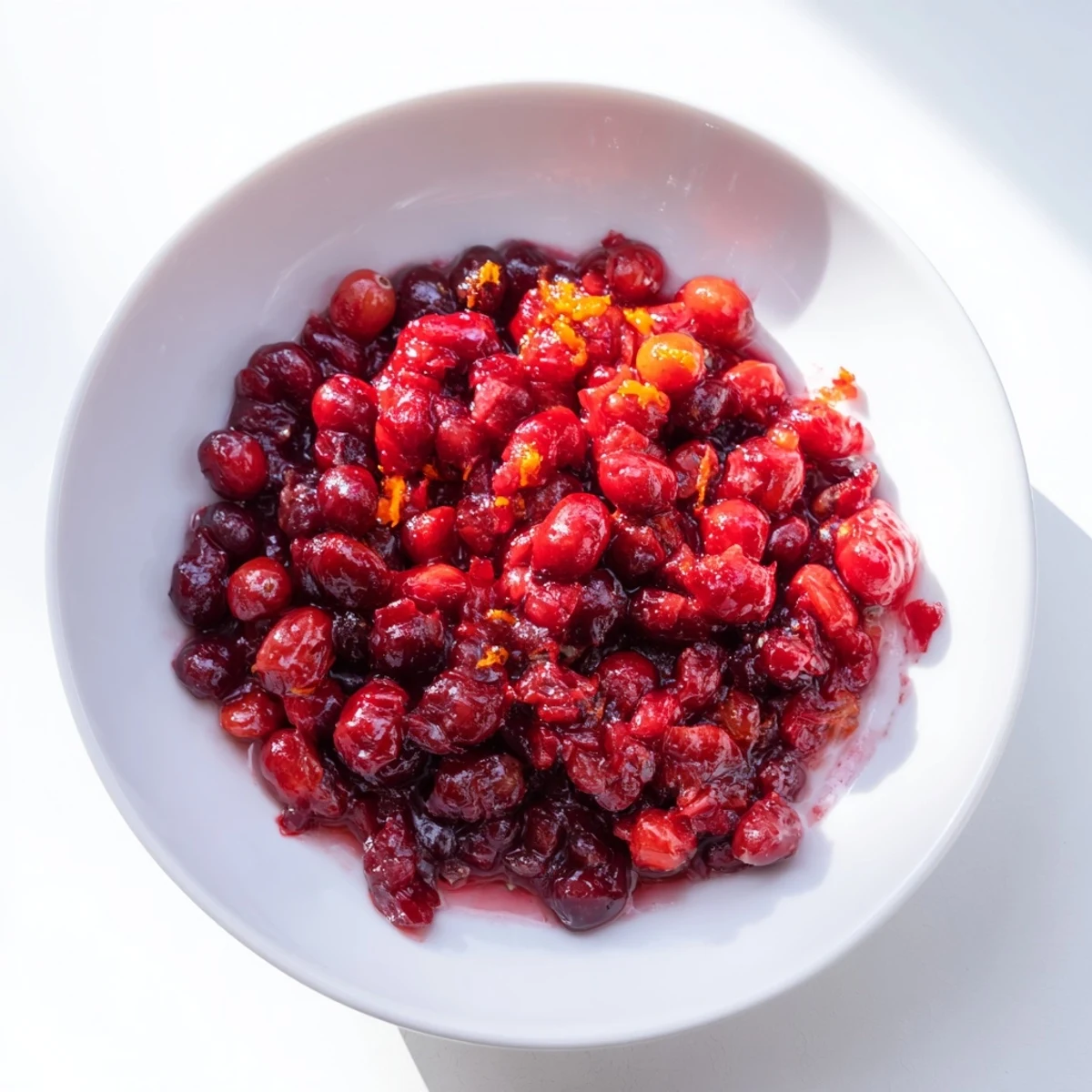 Vibrant cranberry sauce bubbling in a saucepan, ready for Thanksgiving dinner or holiday meals.