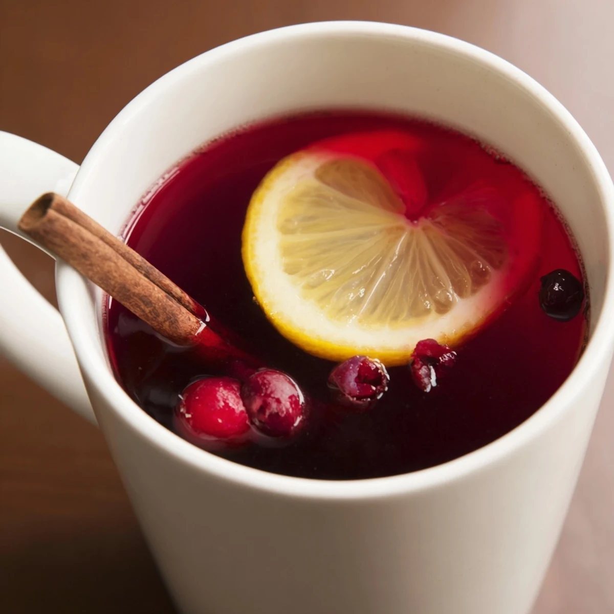 A warm glass of cranberry tea with lemon, steam rising gently from the tart, festive beverage.