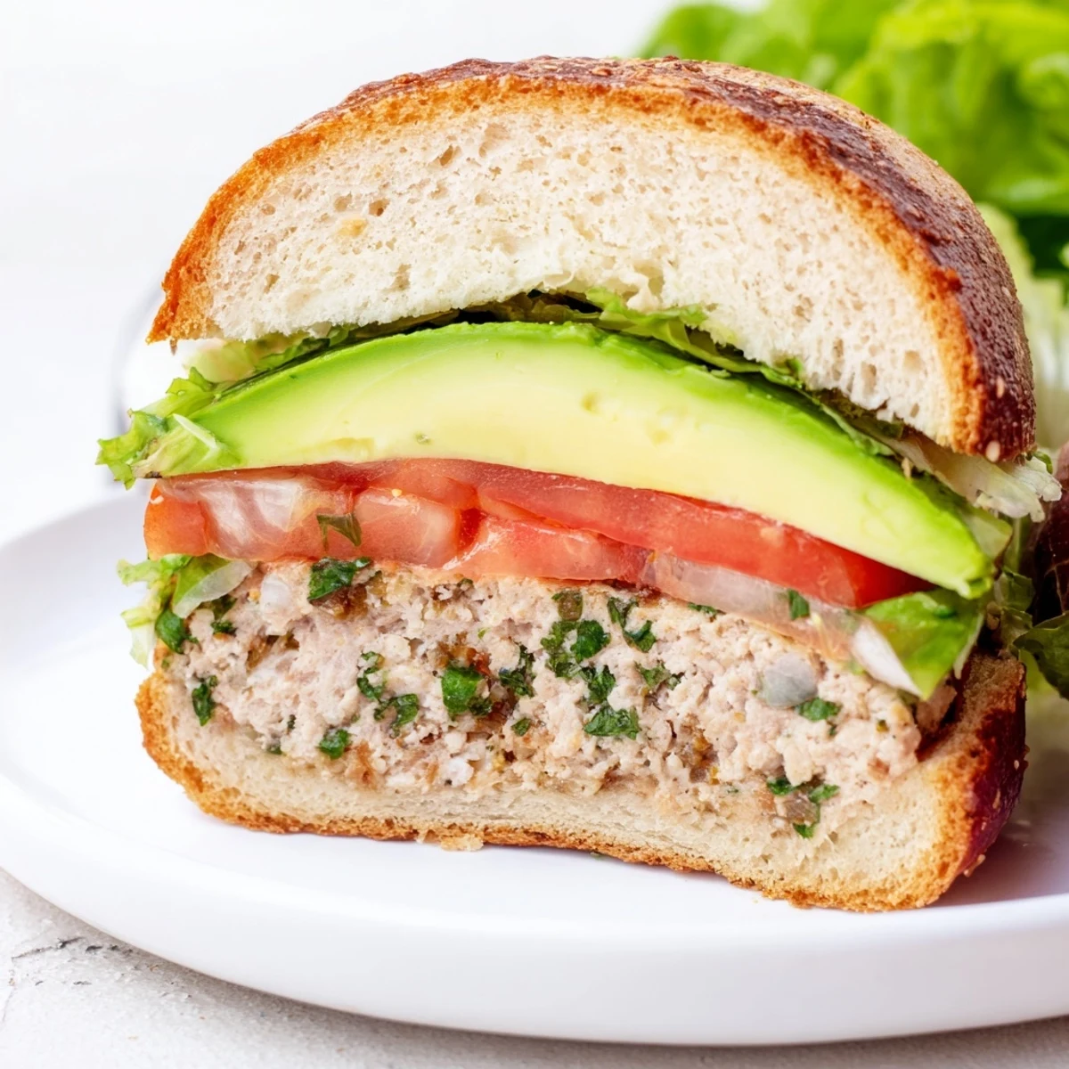 A juicy Turkey Burger with Avocado rests on a toasted whole wheat bun with crisp lettuce and tomato.
