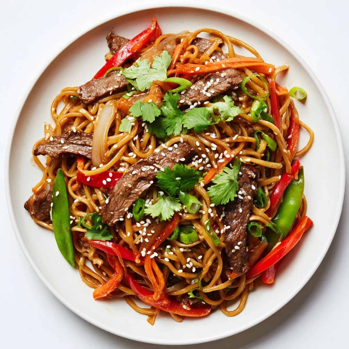 Tender beef strips and noodles coated in a glossy, savory sauce are garnished with sesame seeds.