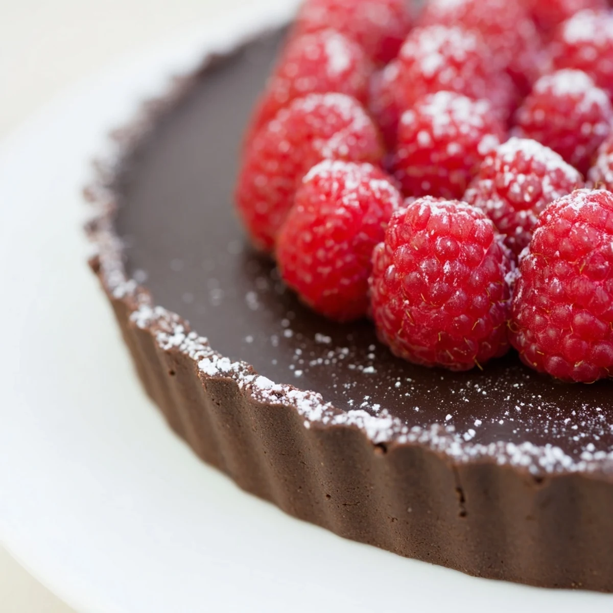A fresh-baked Decadent Dark Chocolate Tart with Raspberries shows glossy filling in a crisp crust, topped with juicy red berries.