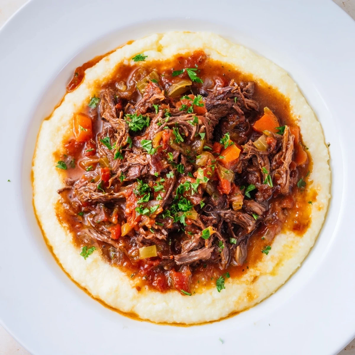 Slow Cooker Beef Ragu with Creamy Polenta served in rustic white bowls, topped with fresh parsley and extra Parmesan cheese for a comforting Italian dinner.