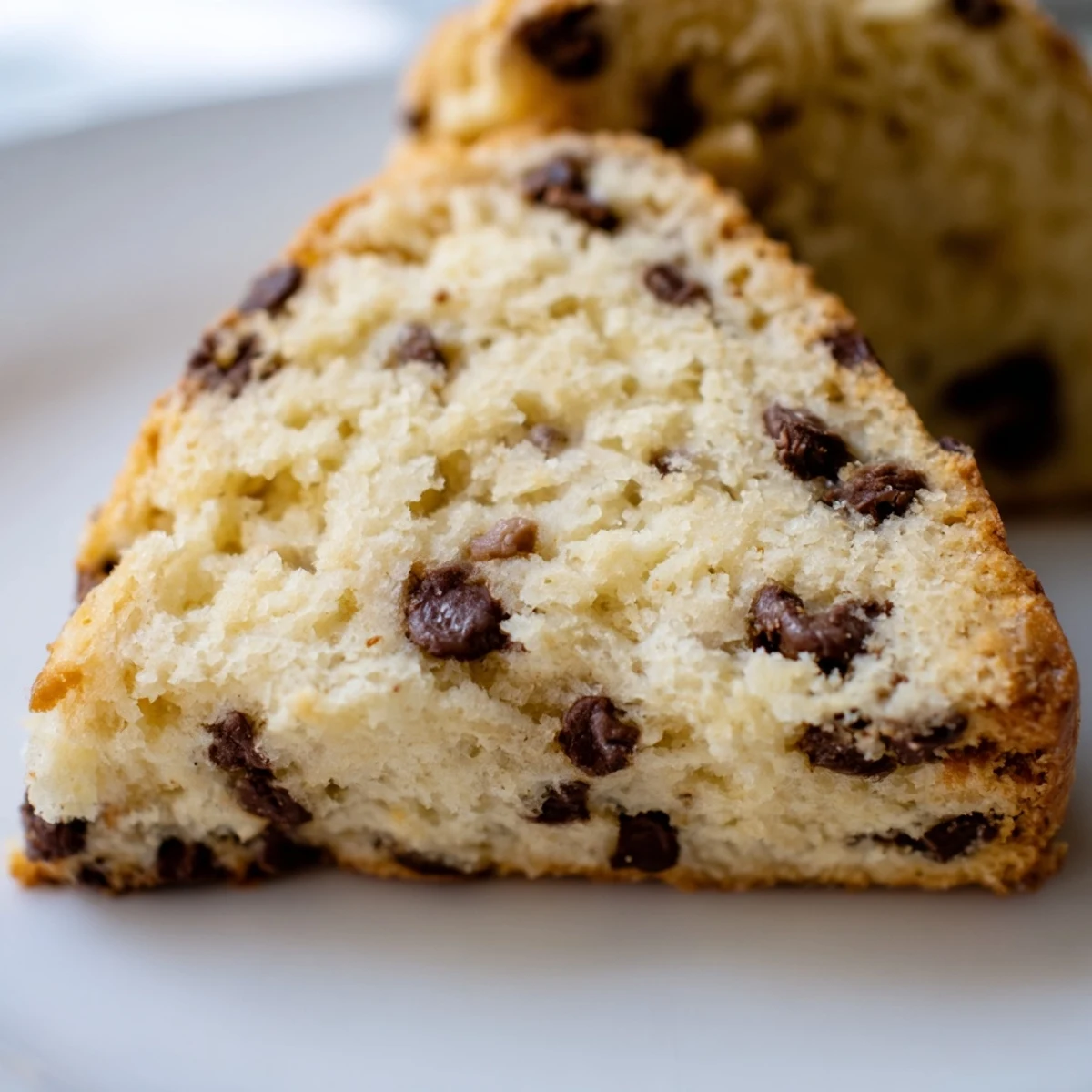 Freshly baked Chocolate Chip Scones on a cooling rack, showing flaky layers and gooey chocolate chips inside.