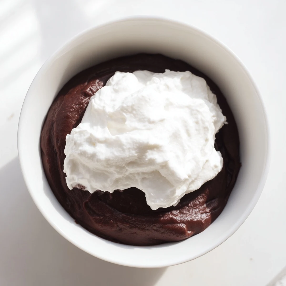 Rich Chocolate Pudding with Whipped Cream topped with soft peaks and fresh raspberries for contrast.