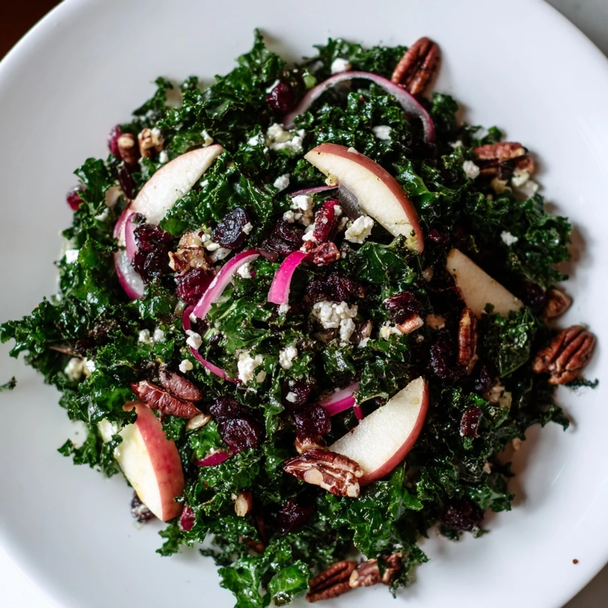 This wholesome Winter Kale Salad with Pecans and Cranberries shows chopped kale, crunchy nuts, ruby cranberries, and creamy feta on a rustic wooden platter.