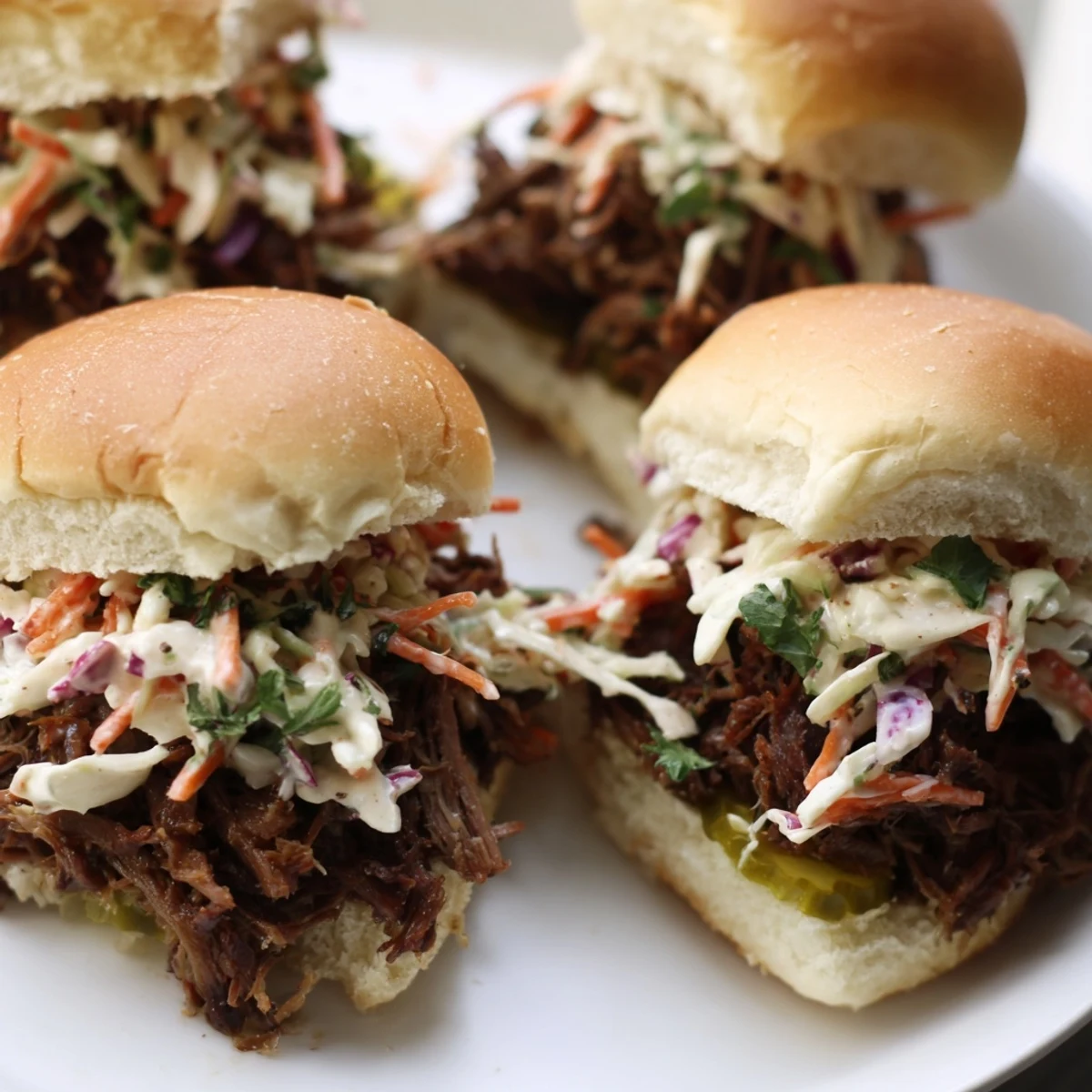 Slow-cooked and shredded beef brisket piled high on soft slider buns, ready to be topped with creamy coleslaw.