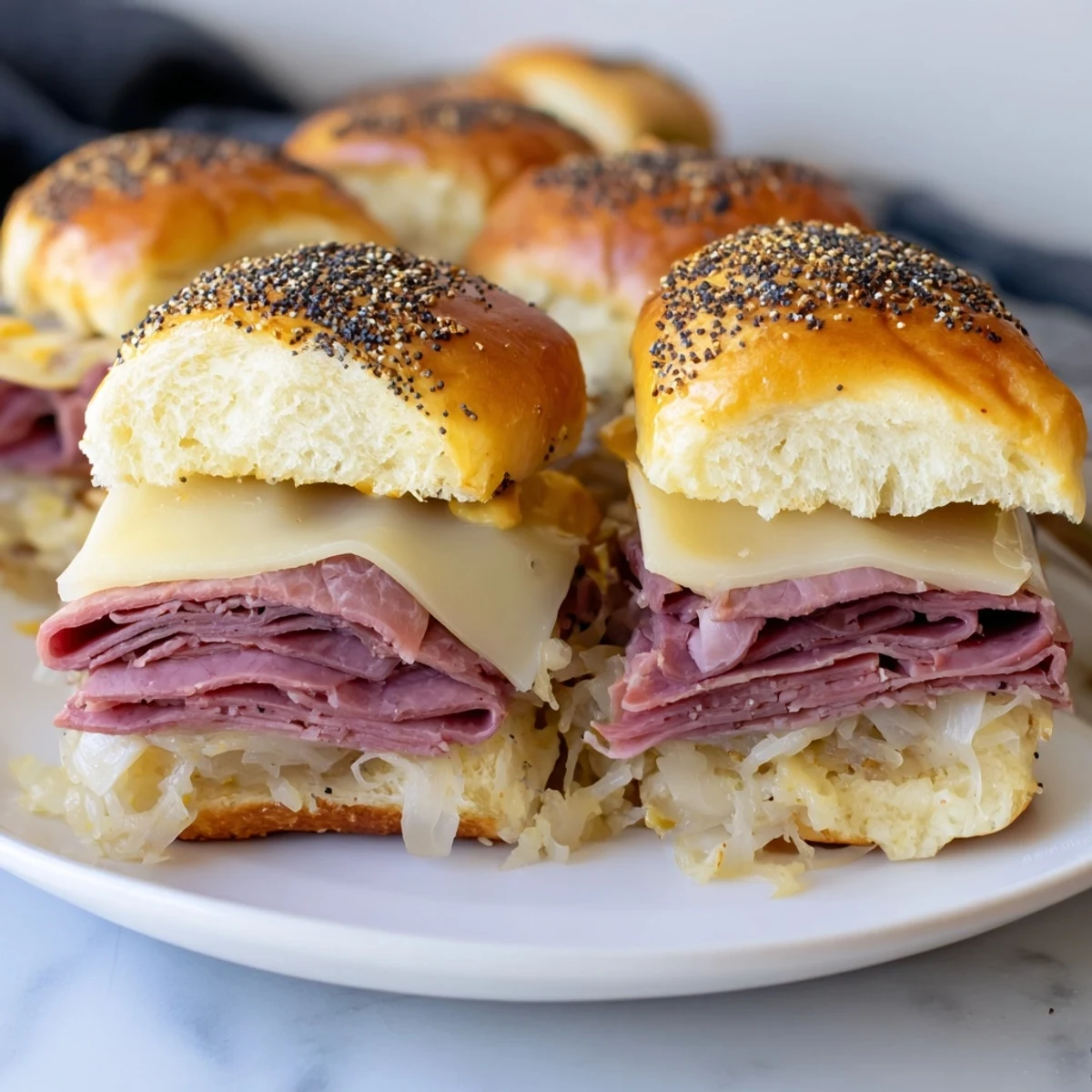 Twelve warm Corned Beef Sliders with Stone Ground Mustard are stacked on a plate beside crisp pickles for a party appetizer.