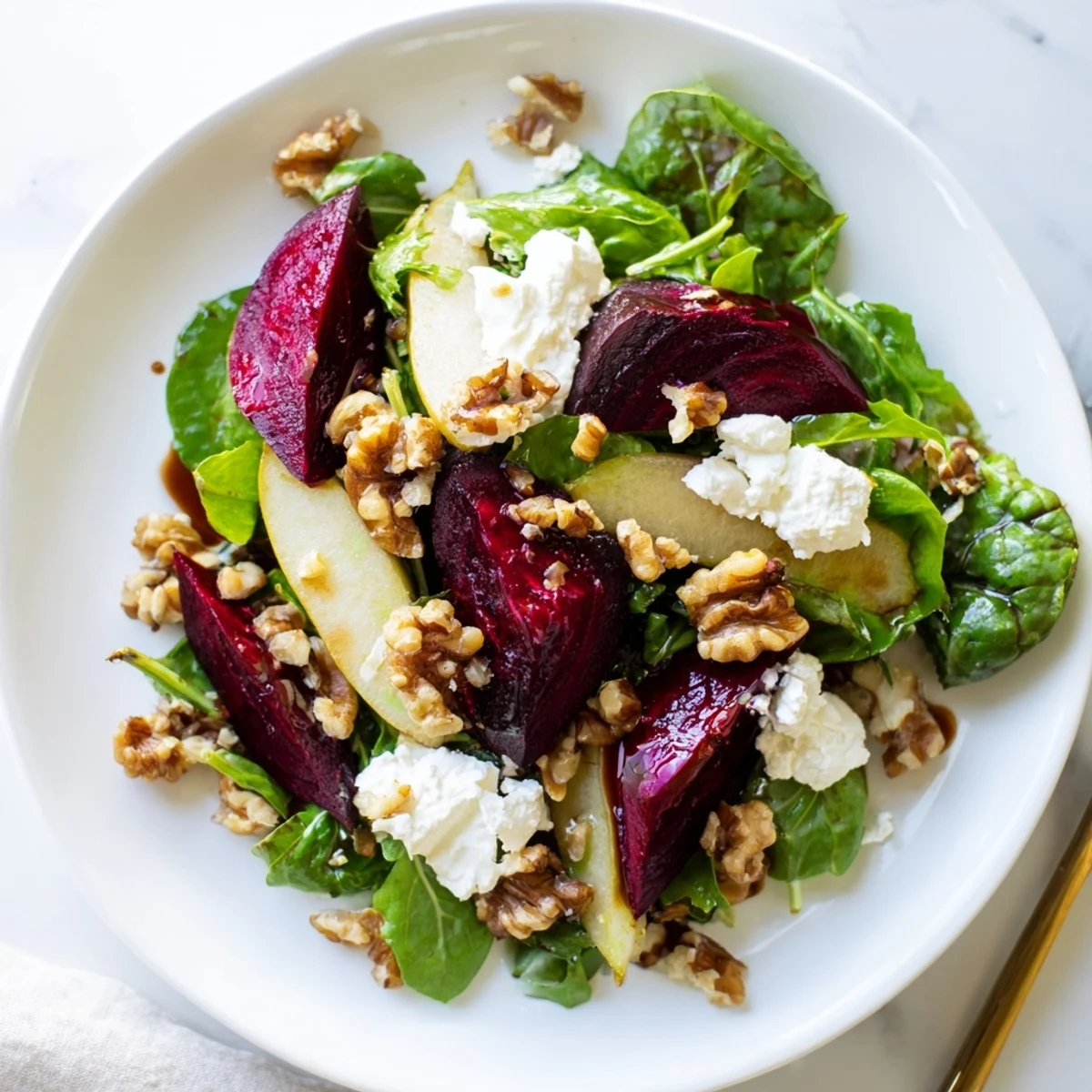 Colorful plate of Roasted Beet Salad with Goat Cheese Crumbles and crisp apple slices for a light vegetarian meal.