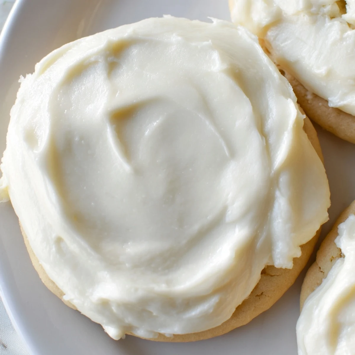A bowl of creamy Easy Sugar Cookie Frosting with a glossy finish ready to spread on vanilla cookies.