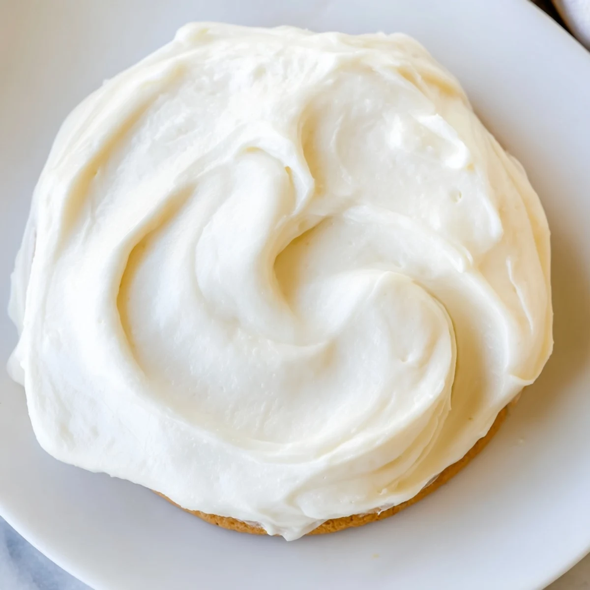 Spatula dipping into Easy Sugar Cookie Frosting showing a smooth texture for decorating festive American cookies.