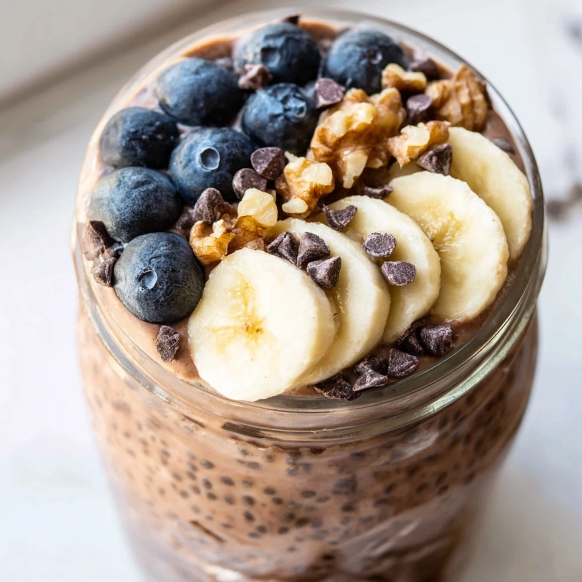 Ultimate Healthy Chocolate Overnight Oats in mason jars with fresh berries and a drizzle of maple syrup