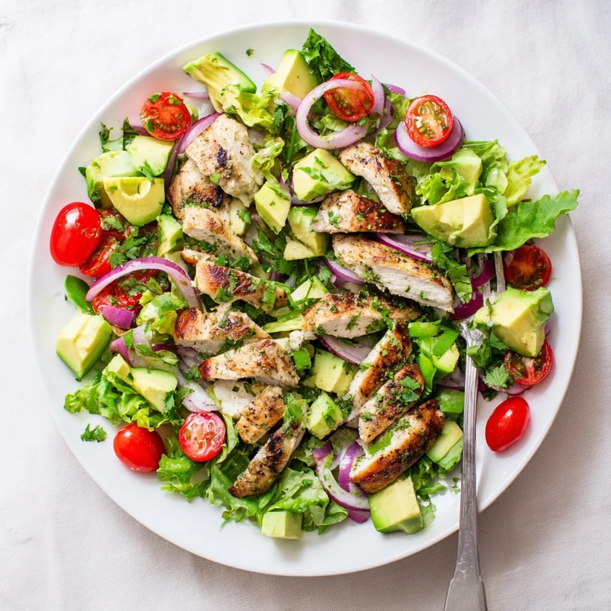 Close-up of Avocado Chicken Salad with tender grilled chicken pieces, diced cucumber, and fresh herbs drizzled with a zesty lime dressing.