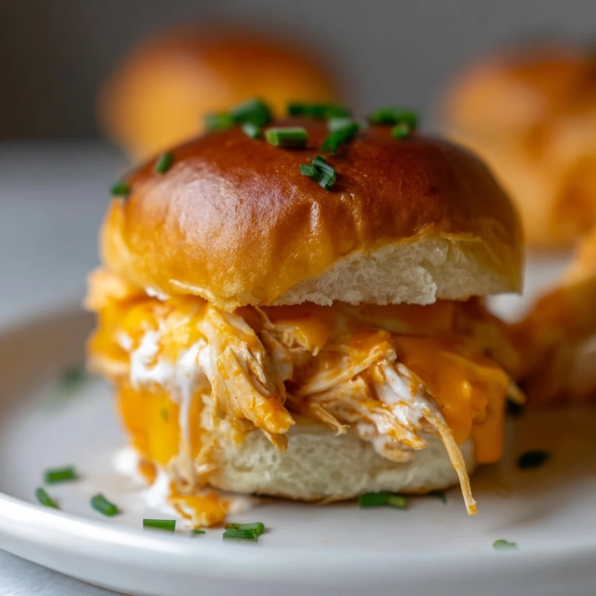 Golden-baked Buffalo Chicken Pizza Dip Sliders with melted mozzarella and cheddar cheese on soft Hawaiian rolls.