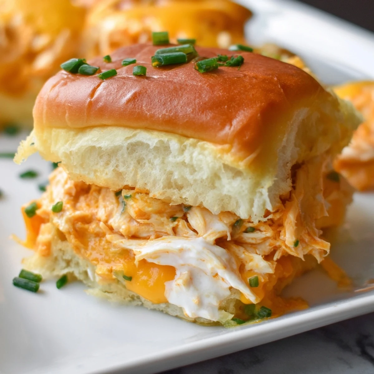 Freshly baked Buffalo Chicken Pizza Dip Sliders with a side of ranch dressing for dipping and celery sticks.