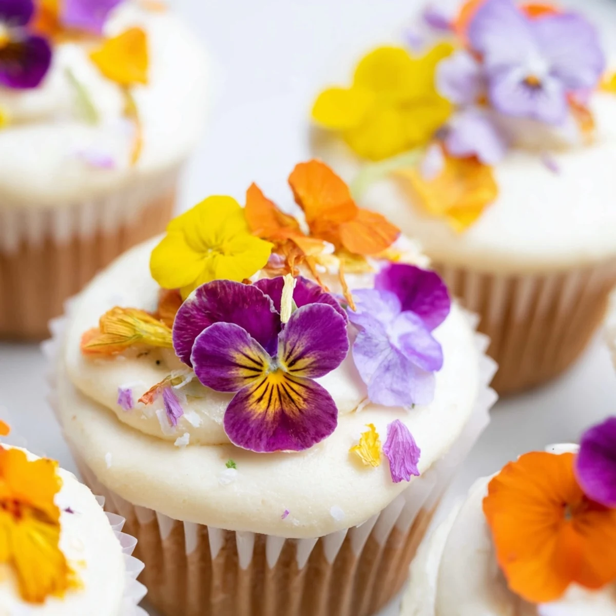 These Wild Flower Cupcakes feature delicate frosting and edible flowers on a marble countertop for spring gatherings.
