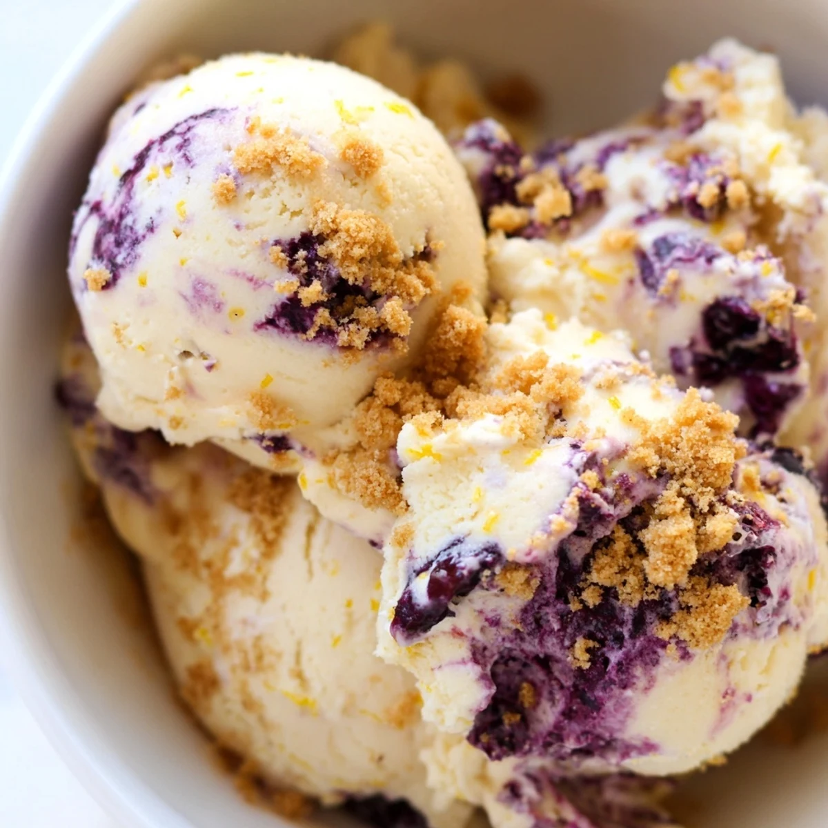 Close-up of churned Lemon Blueberry Cheesecake Ice Cream revealing fresh blueberries and rich cheesecake texture in a frozen treat.