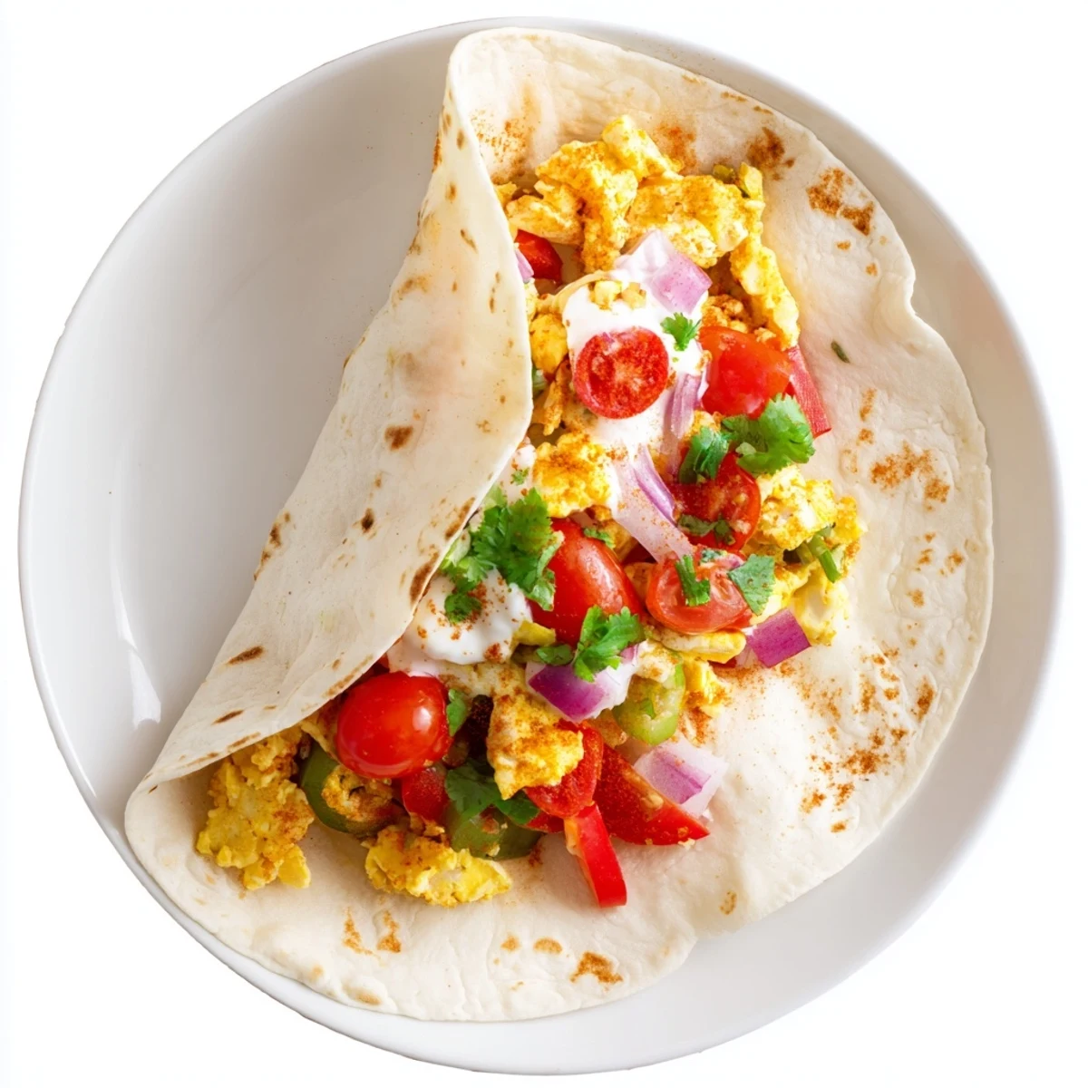 Enjoy the vibrant colors of diced red onion and cherry tomatoes inside this handheld Tex Mex Egg Tortilla Pockets, served hot with a dollop of sour cream.