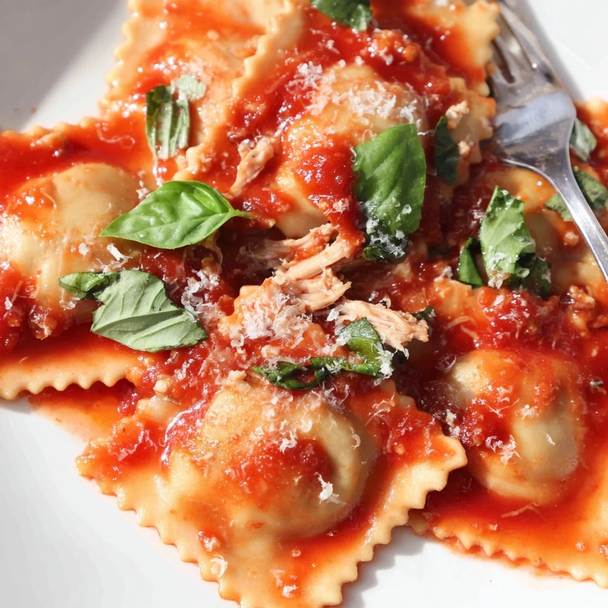 A fork rests beside the Chicken and Mushroom Ravioli with Simple Tomato Sauce, garnished with fresh basil.