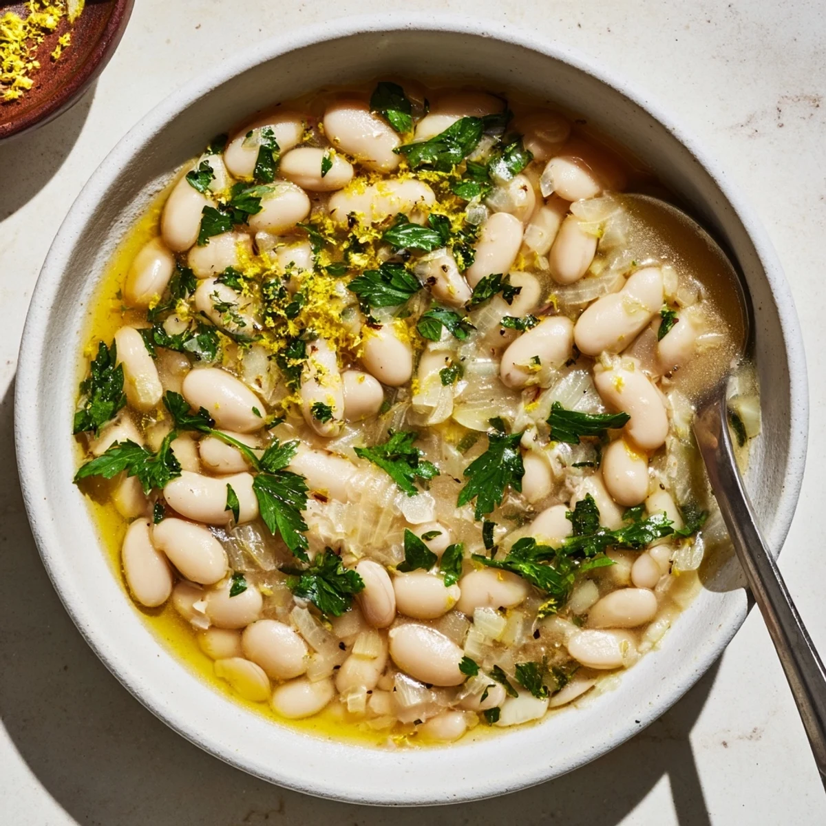Close-up of Miso Butter Brothy Beans showing tender cannellini beans swirled in a buttery miso broth with lemon zest.