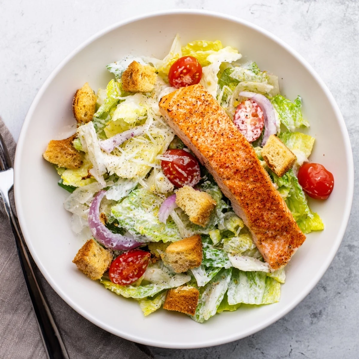 Freshly prepared Salmon Caesar Salad with charred salmon, crunchy croutons, and Parmesan, perfect for lunch.