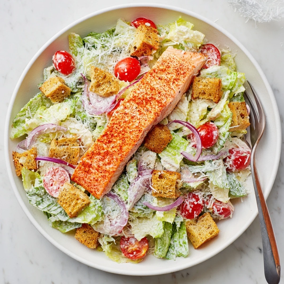 Close-up of a Salmon Caesar Salad featuring juicy salmon, homemade dressing, and cherry tomatoes for color.