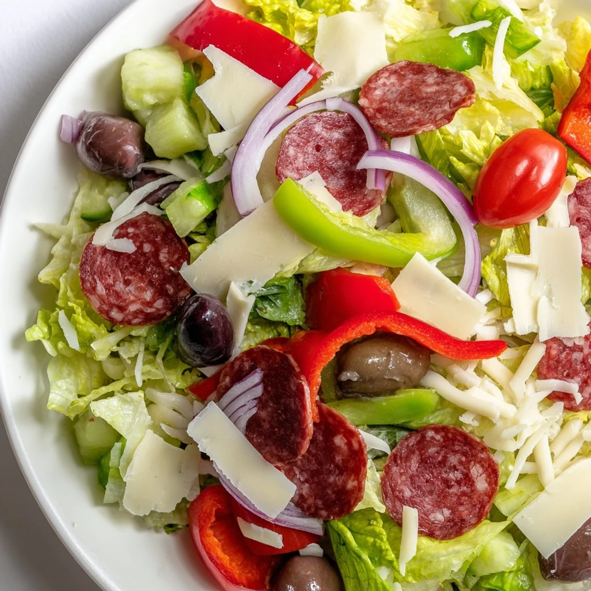 Colorful bowl of Italian chopped salad with fresh vegetables, salami, and mozzarella tossed in zesty homemade dressing