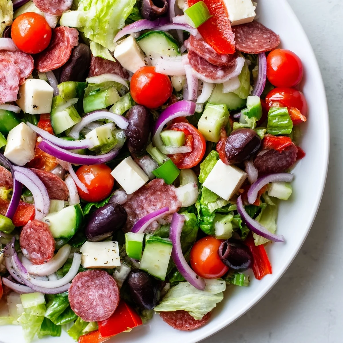 Vibrant Italian chopped salad featuring crisp romaine, tomatoes, olives, and cheese drizzled with tangy homemade Italian dressing