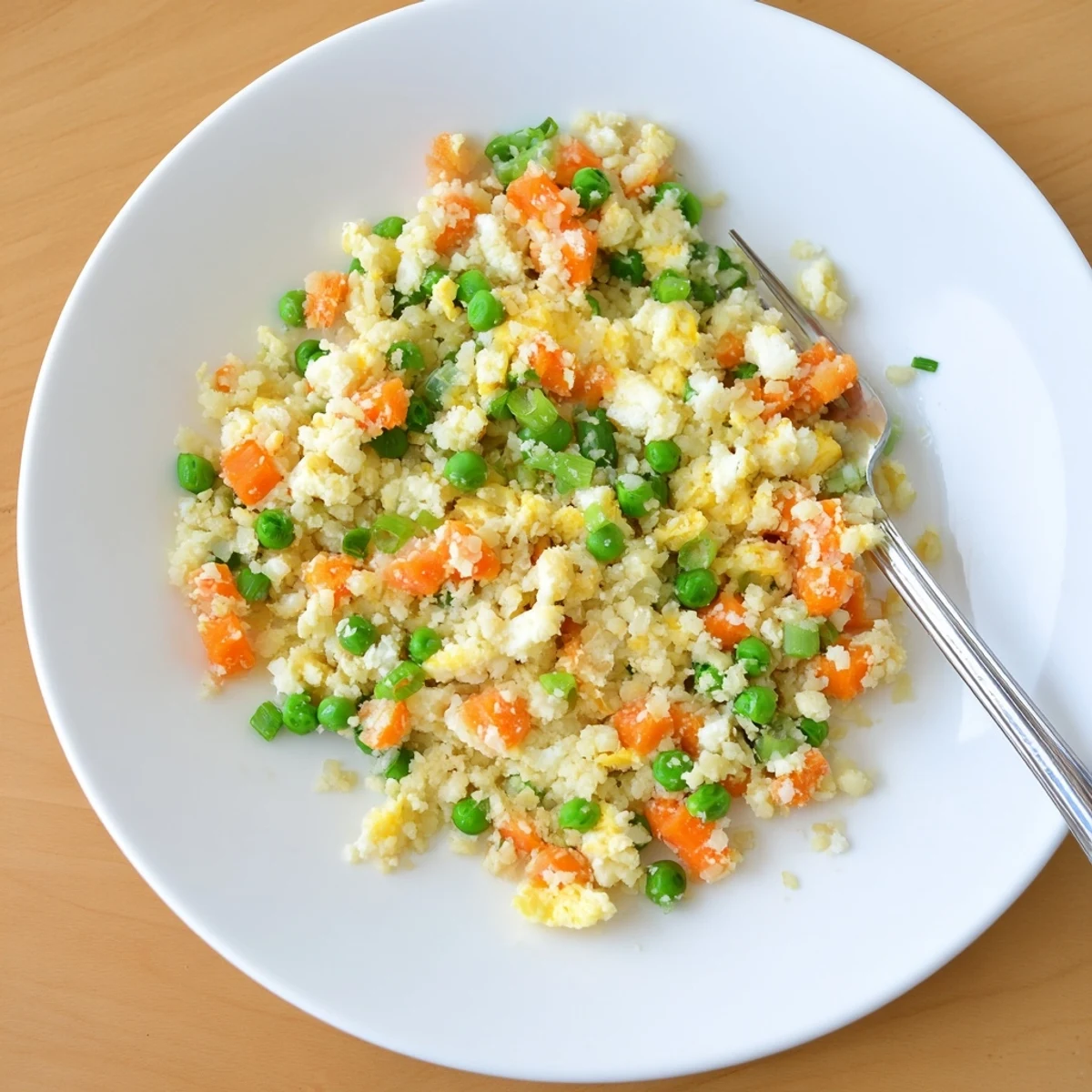 Close-up of vegetable-packed cauliflower fried rice served in a dark bowl with chopsticks
