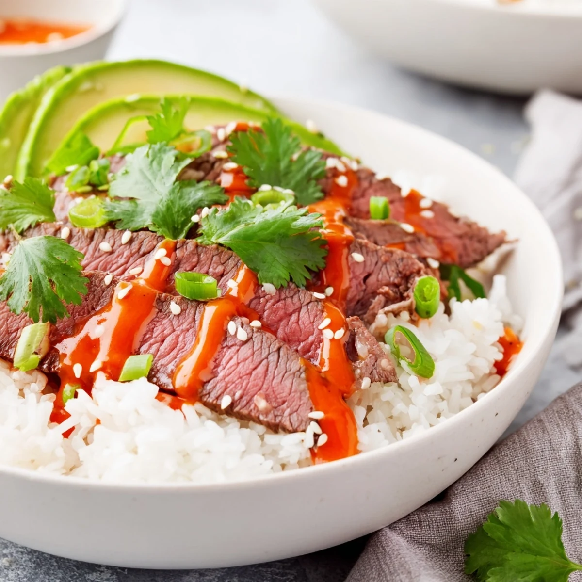 Colorful flank steak bowl with marinated grilled steak, avocado slices, cucumber, and zesty mayonnaise sauce