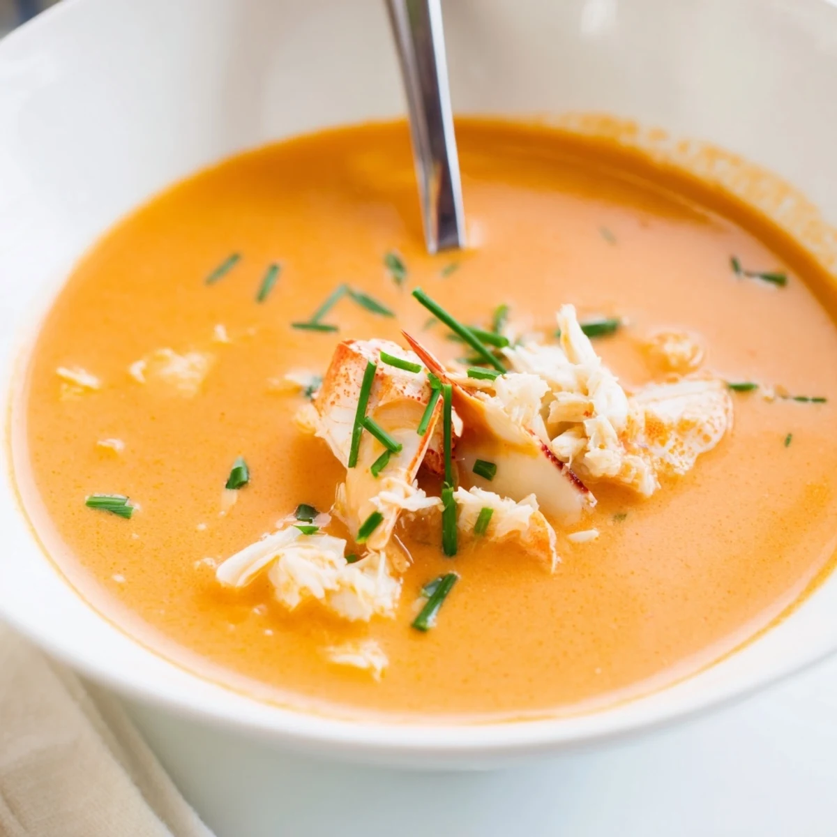 Steaming hot seafood bisque with succulent shrimp chunks and sweet crab in a white ceramic bowl