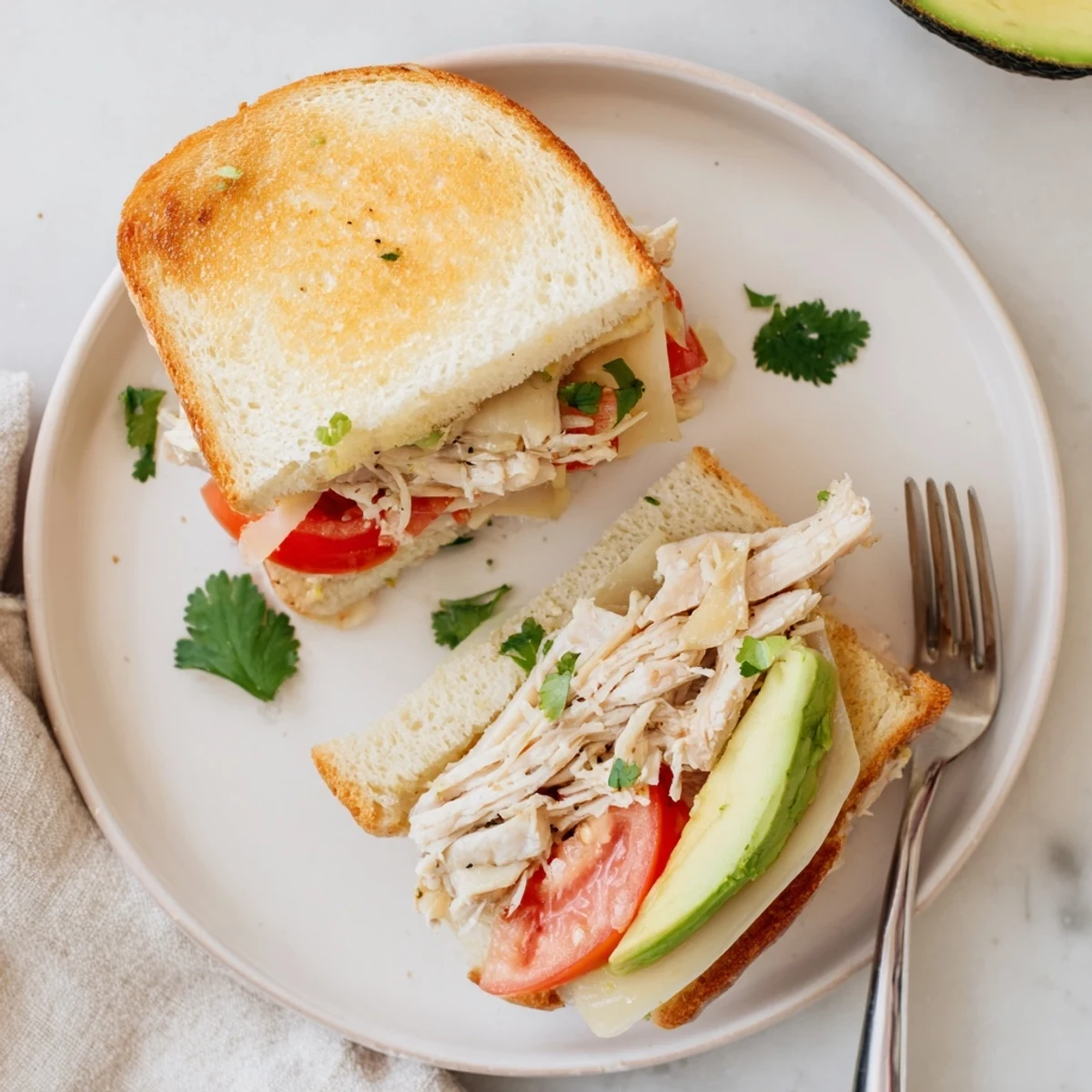 Toasted chicken avocado melt sandwich layered with ripe slices and gooey melted cheese