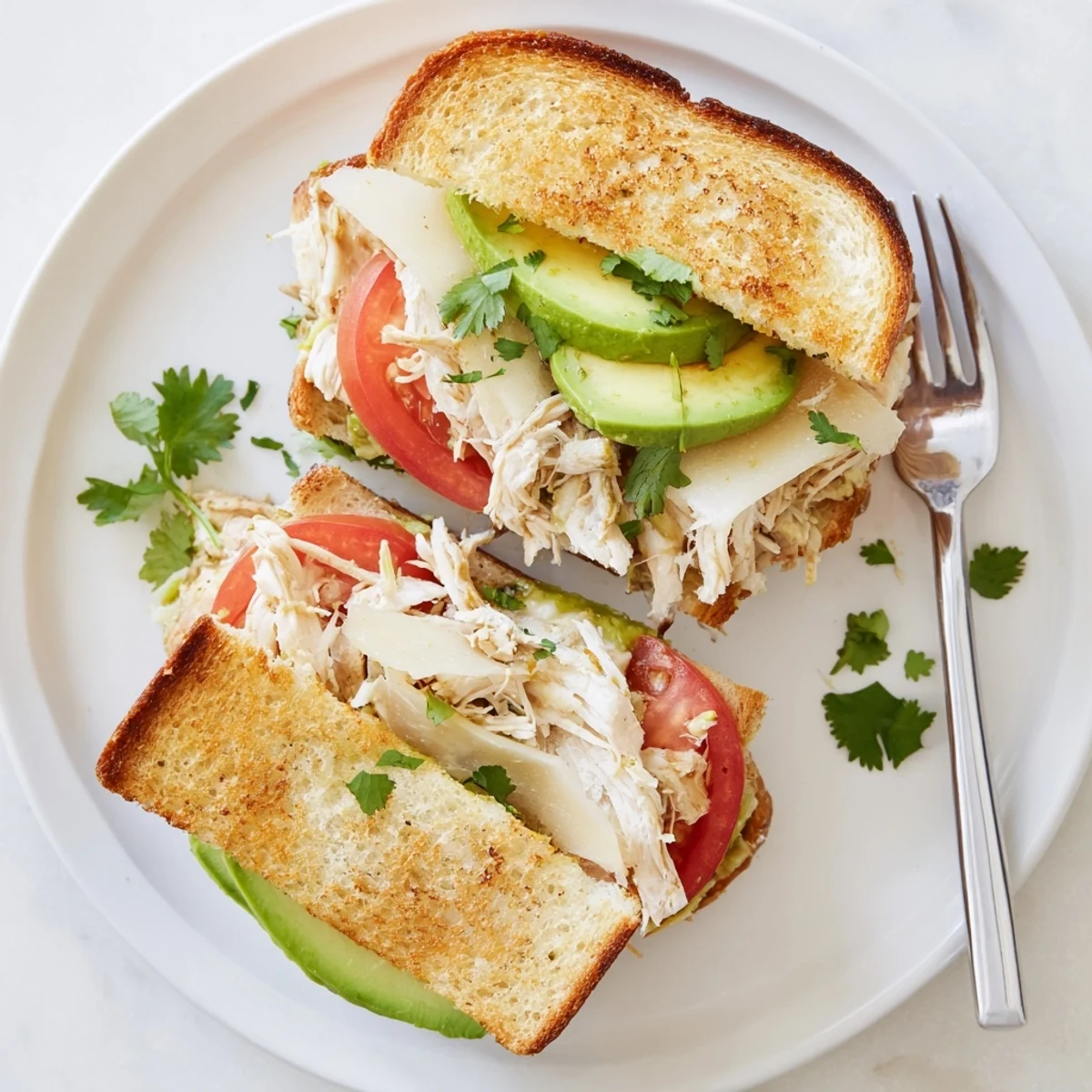 Warm open-faced chicken avocado melt sandwich with juicy chicken and creamy avocado spread
