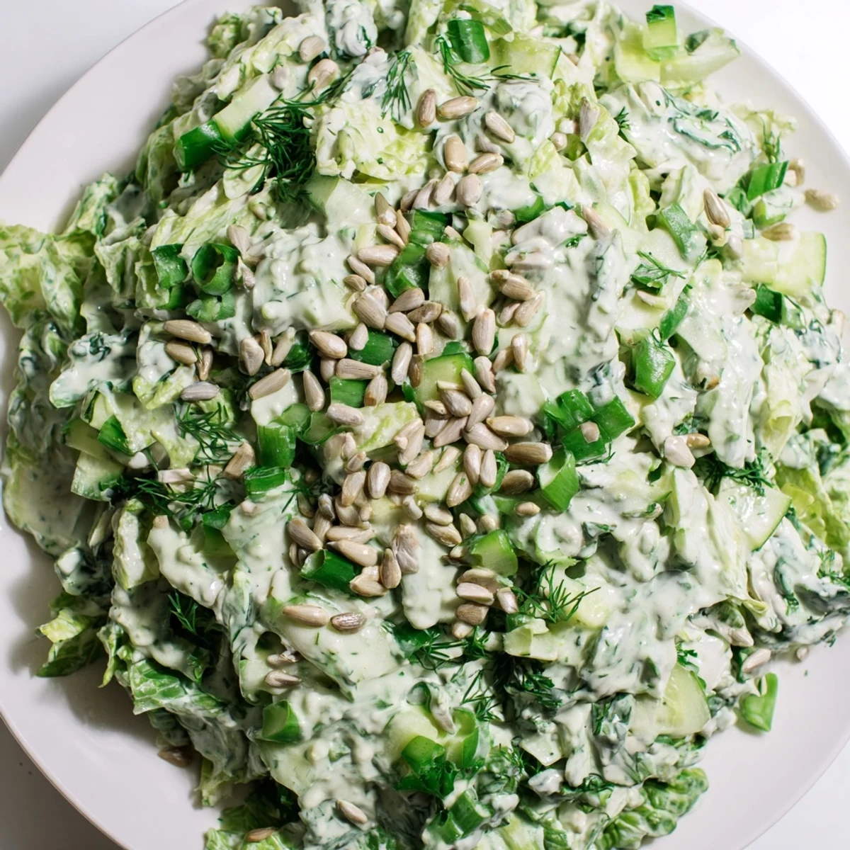 Vibrant Green Goddess Salad featuring chopped romaine and cabbage coated in tangy yogurt-based dressing with pumpkin seeds