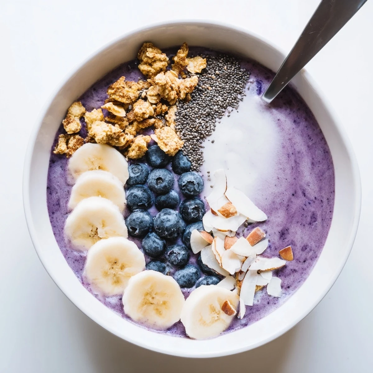 Creamy blueberry smoothie bowl with Greek yogurt topped with fresh berries, granola, and coconut flakes