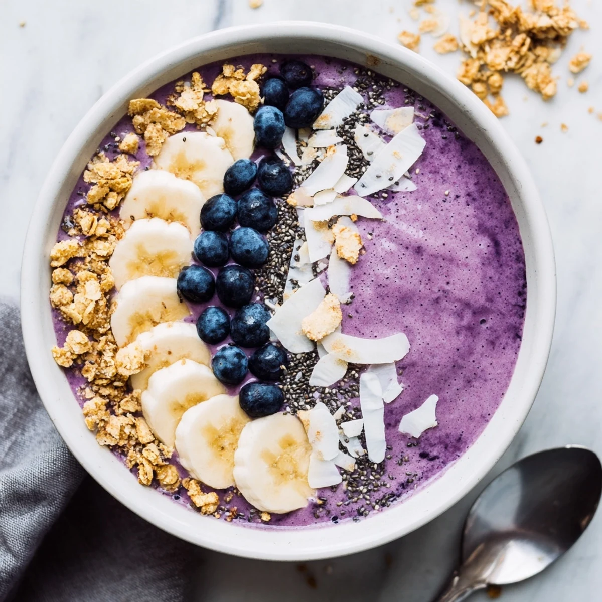 Vibrant breakfast bowl featuring blended blueberry Greek yogurt mixture topped with colorful fresh fruit and granola