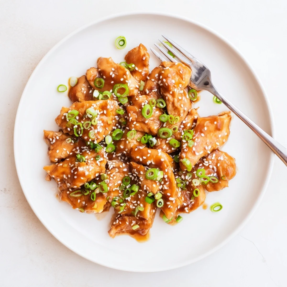 Glossy Crockpot Teriyaki Chicken pieces coated in thick sticky sauce with sesame seeds