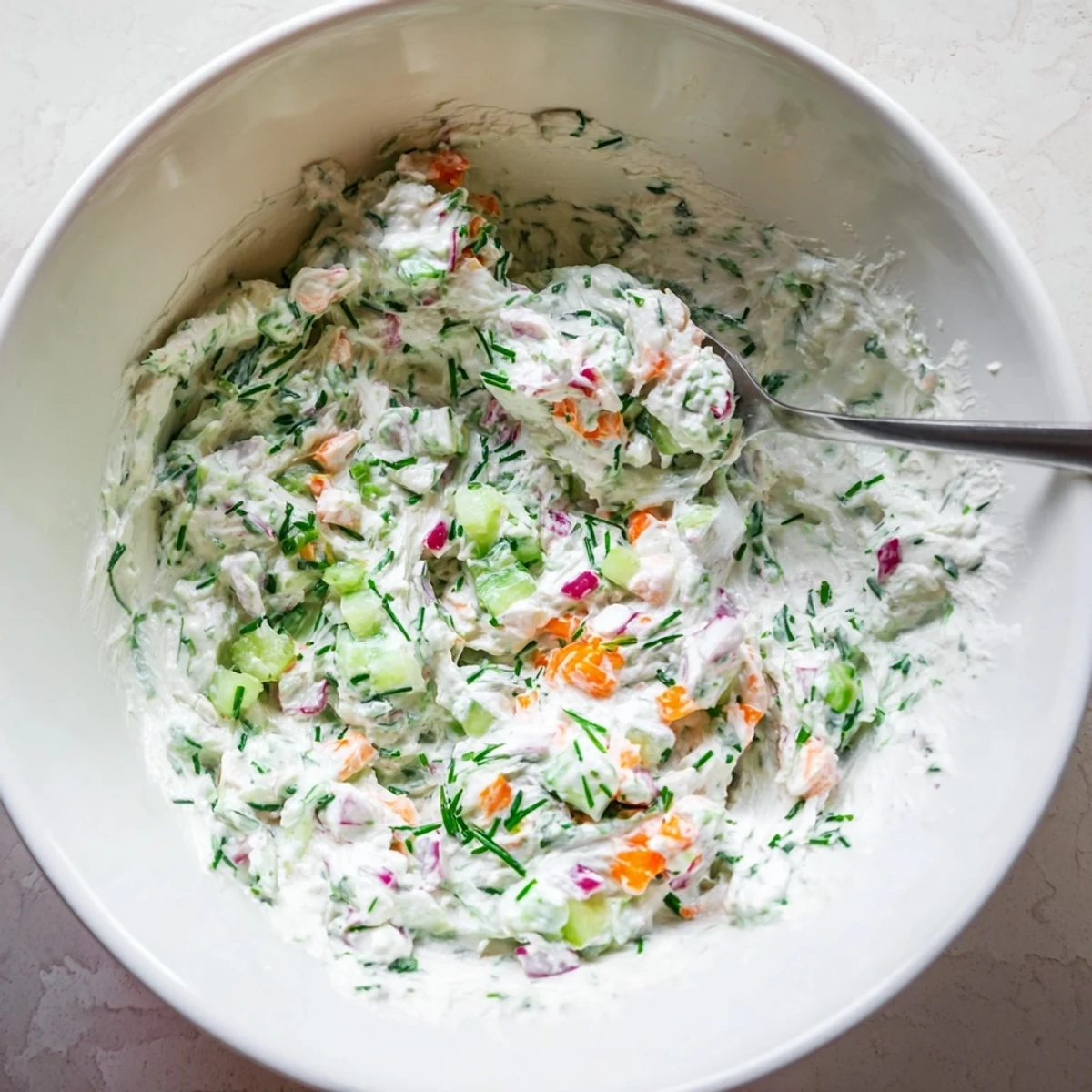 Creamy Easter dip with fresh herbs and colorful vegetables served in a white bowl on a spring table setting