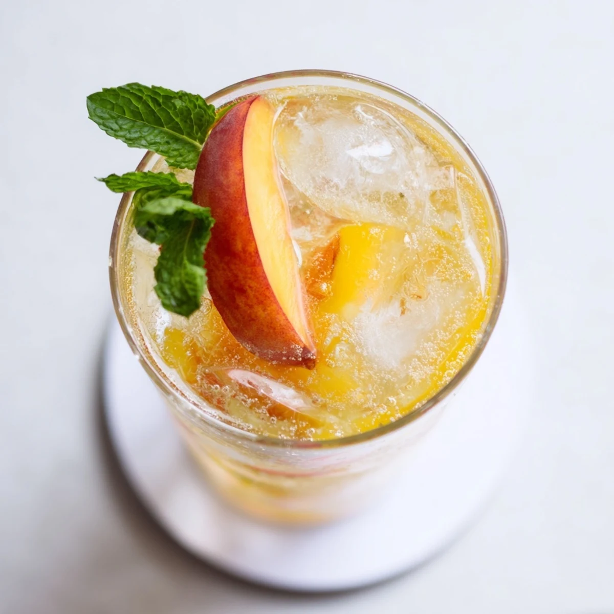 Refreshing ginger peach sparkler drink served in a clear glass with bubbles rising and peach garnish