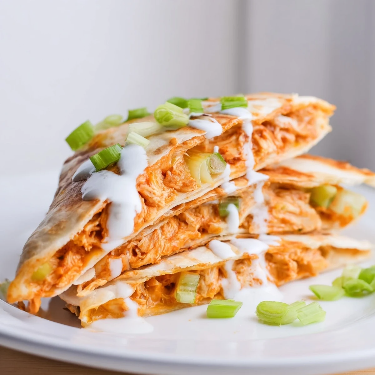 Spicy shredded buffalo chicken and melted cheese inside a flour tortilla wedges with ranch topping