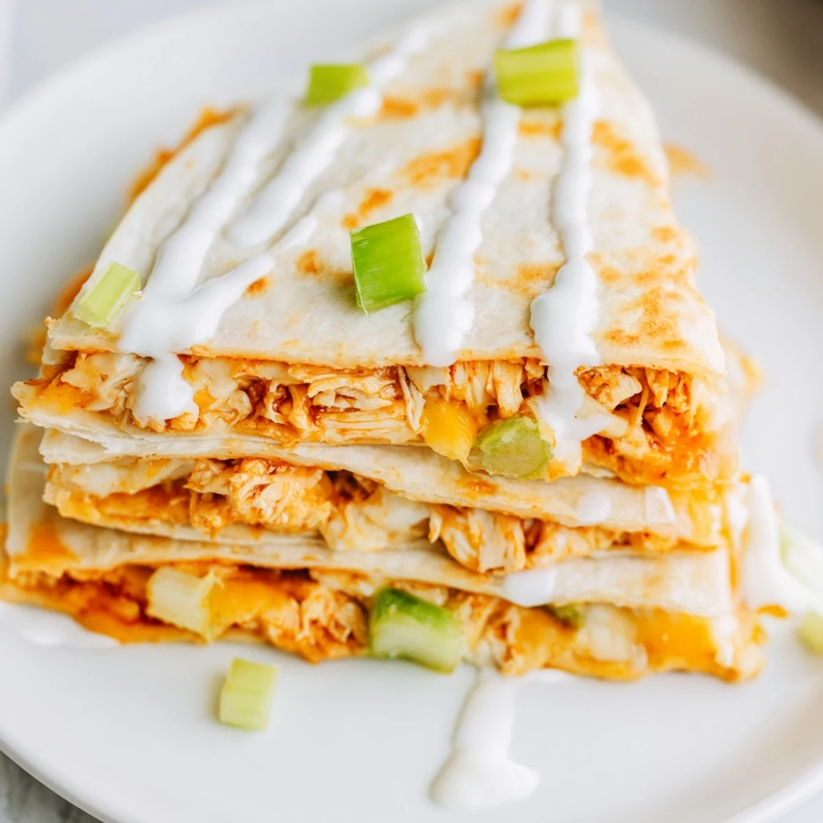 Sliced quesadilla revealing oozing Monterey Jack and cheddar with buffalo chicken and celery bits