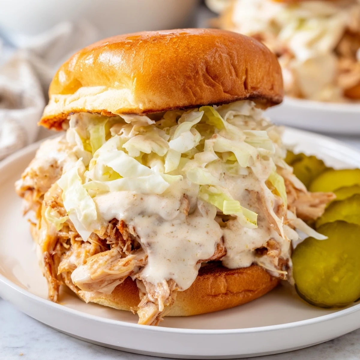 Southern BBQ chicken chopped sandwich featuring white sauce, fresh slaw, and pickles