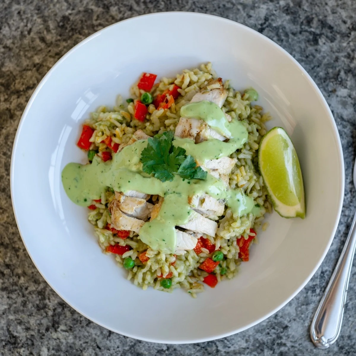 Golden Peruvian chicken rice drizzled with vibrant green sauce and lime wedges