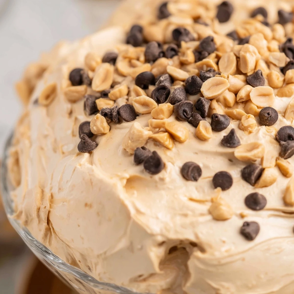 Creamy peanut butter mousse topped with roasted peanuts and mini chocolate chips in a clear glass
