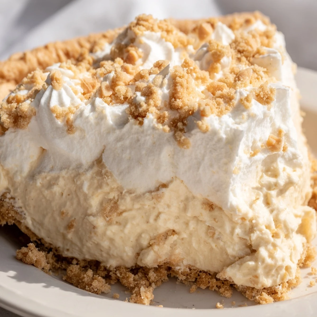 Creamy Amish Peanut Butter Dream Pie topped with fluffy whipped cream and golden crumb topping
